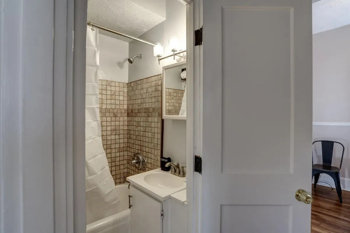 A modern, serene bathroom featuring a glass-enclosed shower, a sleek sink, and a large mirror. The clean design and gentle lighting convey a sense of privacy and relaxation, ideal for unwinding after a long day.