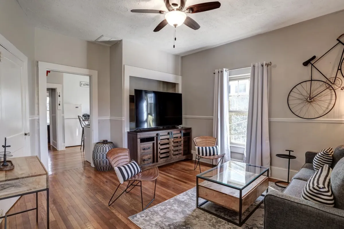 This image presents a casual and comfortably furnished living area with a television, sofa, coffee table, and distinctive bicycle decoration. The layout is perfect for settling in after a day of adventure, with a vibe that encourages both socializing and quiet relaxation.